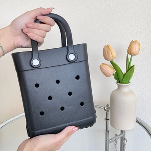 Detail of waterproof black EVA tote bag with hole design held by hand in stylish setting