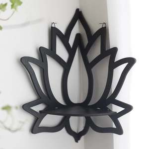 Detail of black lotus-shaped wooden corner shelf mounted on a white wall with soft lighting