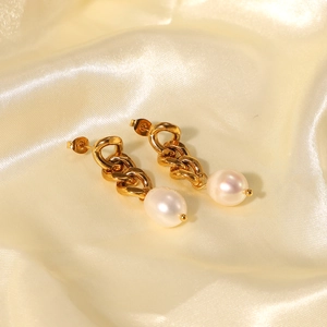Macro detail of 18K gold-plated baroque pearl earrings on elegant golden silk fabric