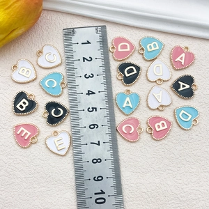 Macro shot of 13mm heart-shaped alloy alphabet pendants in various enamel colors