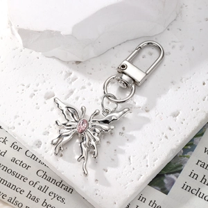 Macro shot of silver metal butterfly keychain with pink gemstone on vintage background