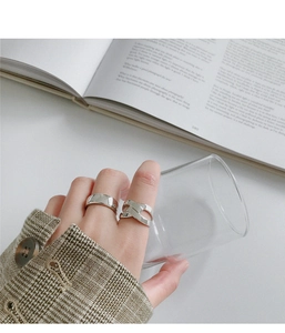 Close-up of minimalist silver rings with smooth surface and woven design on hand