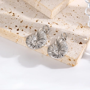 Macro shot of silver shell pendants with intricate textures on a beige stone surface