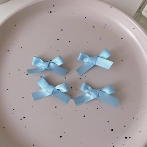 Detailed view of four light blue satin ribbon bows placed on a pink polka dot ceramic tray