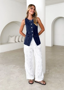 Detail of dark blue denim vest paired with white lace pattern wide-leg trousers