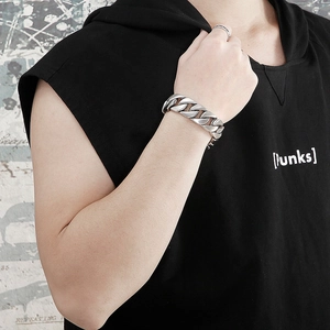 Detailed view of 20mm matte silver Cuban link bracelet and textured ring on male model