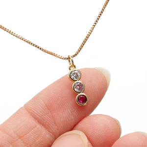 Gold snake necklace with vertically stacked white, pink, and red cubic zirconia stones