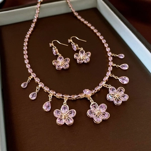 Detailed view of vintage gold necklace and earring set with pink gems in a gift box