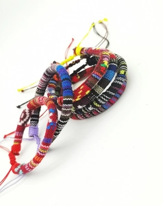 Detailed view of stacked colorful handmade woven cotton surf bracelets on white background