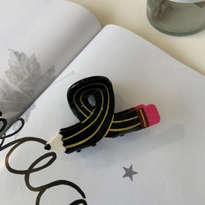 Cute pencil-shaped acetate hair claw clip in candy colors on an open book