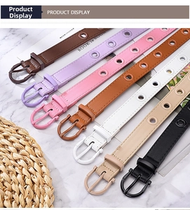 Set of multi-color skinny belts with silver eyelets and matching buckles on marble surface