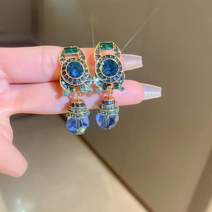 Macro detail of vintage gold drop earrings with blue and green crystals and tassels