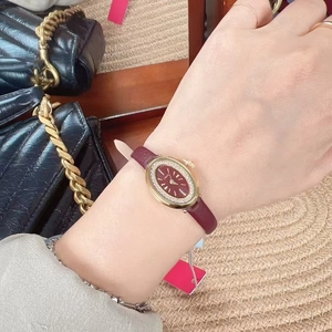 Close-up of a women's gold oval watch with burgundy leather strap and diamond dial