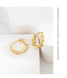 Detailed view of gold plated hollow heart earrings on white geometric stands