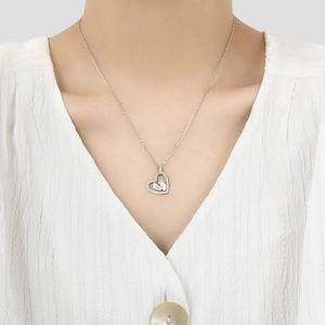 Silver heart pendant necklace with baby footprints charm worn by a female model