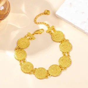 Detailed view of golden coin bracelet with embossed portrait charms and a heart pendant