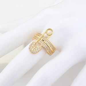 Detailed view of a gold safety pin ring with micro-pave zircons on a white hand model