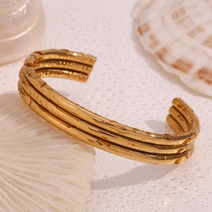 Macro detail of triple-layered 18K gold plated stainless steel open bangle with water drops