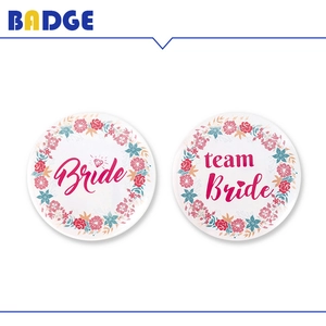 Detailed view of floral Bride and Team Bride tinplate badges with pink flower wreaths