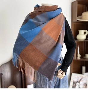 Close-up of soft plaid scarf showing blue and brown knit texture and handmade fringe tassels