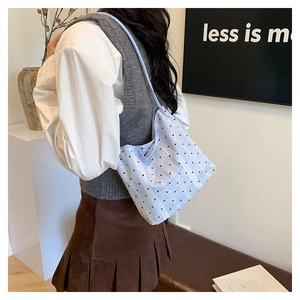 Close-up of light blue polka dot bucket bag worn by a model in a natural setting