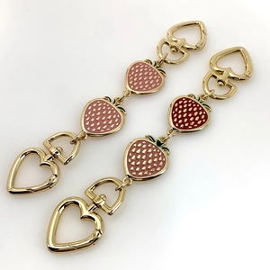 Detail of pink strawberry bag extension chain with heart-shaped clasps and gold finish