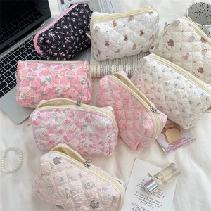 Flat lay of quilted cotton cosmetic bags in floral and animal prints with metal zippers