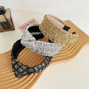 Detailed view of textured metal knot headbands in gold, silver, and black on a tray
