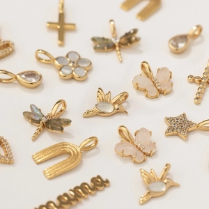 Detailed close-up of assorted gold charm pendants featuring crosses, butterflies, and stars