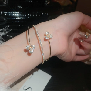 Detail of gold flower bangle with pearls and micro-pave zircons on a female wrist