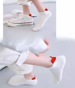 Detail of white cotton ankle socks featuring a distinctive red heart shape on the heel