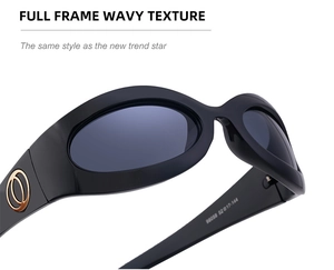 Detail view of black Y2K oval sunglasses featuring gold circular metal accents and branding