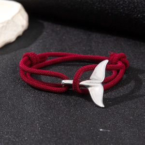 Detail of red braided cord bracelet with silver whale tail pendant and adjustable knot