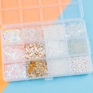 Detail of 12-slot storage box with white pearls, sequins, and shell flakes for DIY crafts