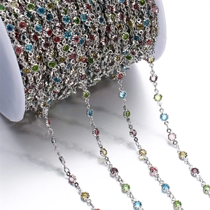 Detail of silver chain on white spool featuring colorful rhinestone flower charms