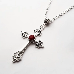 Gothic silver cross necklace featuring a vibrant red gemstone centerpiece on white background