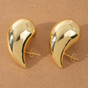 Macro detail of polished gold teardrop earrings showing smooth metallic finish and backings