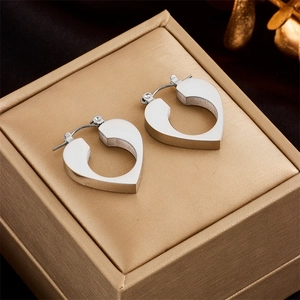 Minimalist silver heart-shaped stainless steel hoop earrings on a velvet jewelry box