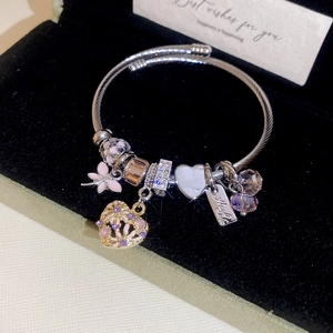 Detail of silver woven bracelet with pink heart charms and purple crystal beads in a box