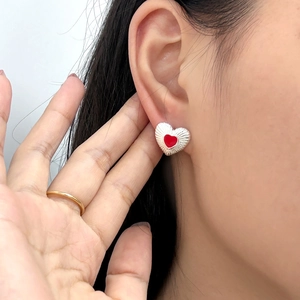 Close-up of 925 silver red heart stud earrings worn elegantly on the ear lobe