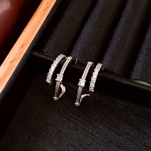 Elegant double-layered C-shaped silver earrings with sparkling zircon on black velvet