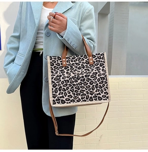 Detailed view of leopard print tote bag with brown leather handles and crossbody strap