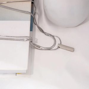 Detailed view of silver rectangular pendant on a sleek snake chain necklace