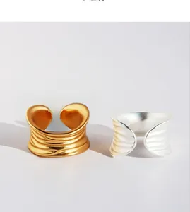 Detailed view of matte gold and silver wave rings with unique pleated texture and open design