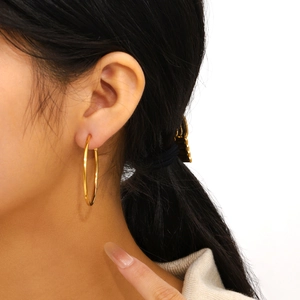 Minimalist gold plated stainless steel hoop earrings worn on a female model side view