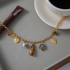 Detailed close-up of multi-pendant gold necklace with resin beads and coin charms