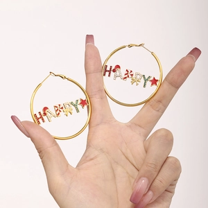 Macro shot of gold hoop earrings with festive HAPPY charms and colorful zircons