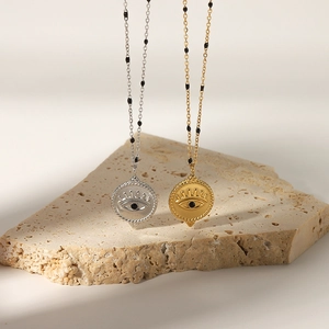 Gold and silver evil eye pendant necklaces with zircon on natural stone display