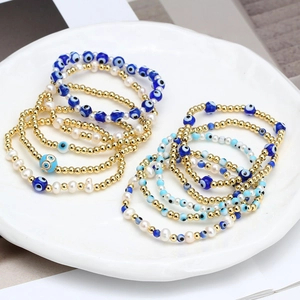 Blue evil eye beaded bracelet set with gold metal beads and white pearls in a tray