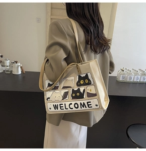Detail of cute cat illustration and Welcome text on a beige canvas tote bag for women